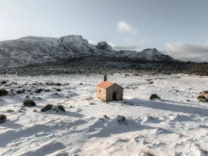 planalto cheio de neve com uma casota de madeira ao meio